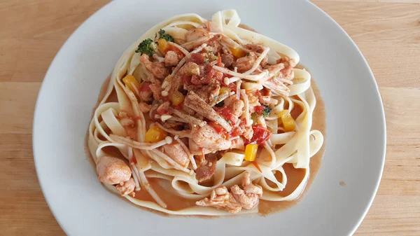 Homemade chicken pasta served on wooden table.