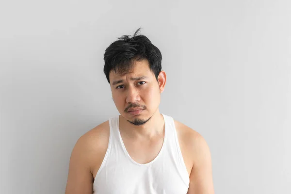 Poor and depressed man wear white tank top on grey background. Concept of desperate life.