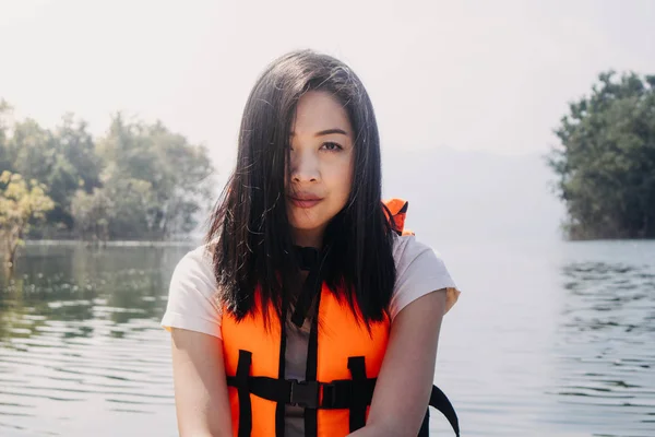 女人穿着鲜活的橙色救生衣或救生衣在湖中的皮划艇上. — 图库照片