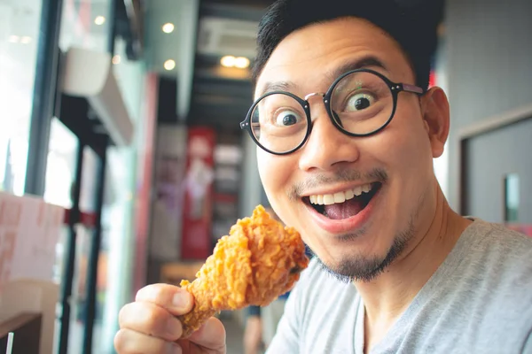 Funny face of man eat fried chicken in the franchise cafe.