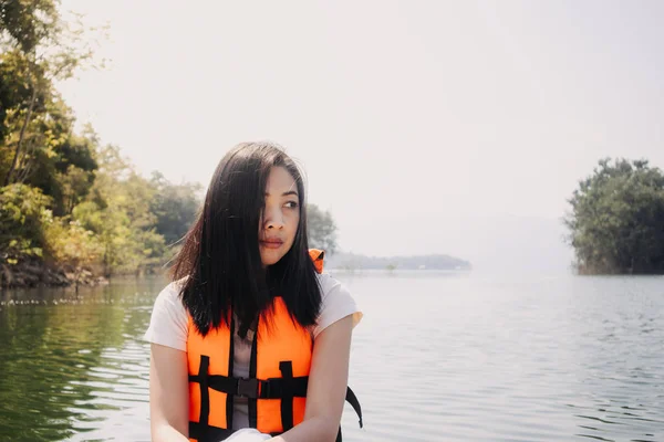 Frau trägt leuchtend orangefarbene Schwimmweste oder Schwimmweste auf Kajak im See. — Stockfoto