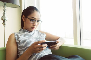 Kadın kanepede mobil oyun oynamaya konsantre.