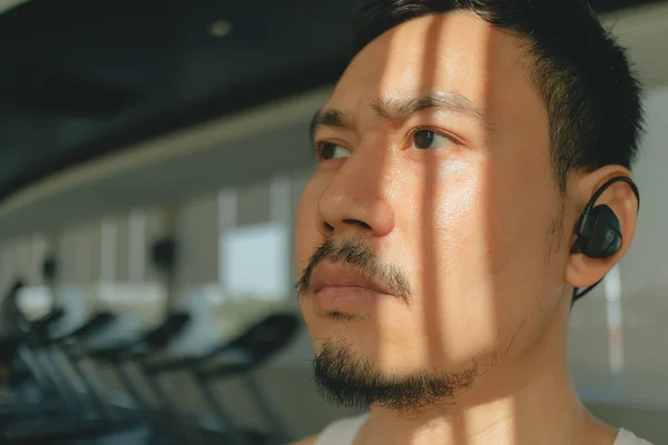 Serious face of Asian man in the fitness gym.