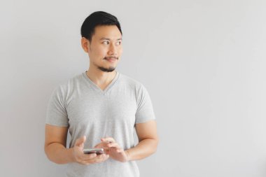 Gri tişörtlü adam akıllı telefonu kullanıyor.