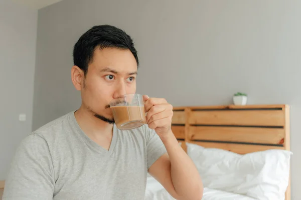 남자는 자신의 침실에서 침대에 커피 한 잔을 마시고있다. — 스톡 사진