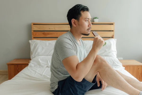 Homem está bebendo uma xícara de café na cama em seu quarto . — Fotografia de Stock