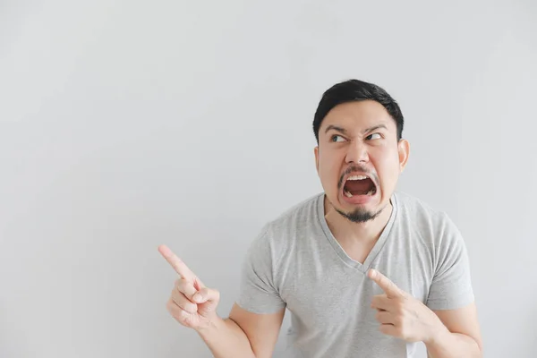 Cara irritada de homem em camiseta cinza com ponto de mão no espaço vazio . — Fotografia de Stock