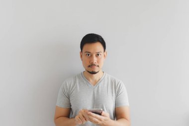 Gri tişörtlü adam akıllı telefonu kullanıyor.