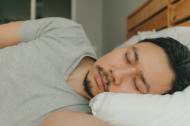 Yorgun suratla yatağında uyuyan adamı kapatın. Yorgun uyku kavramı.