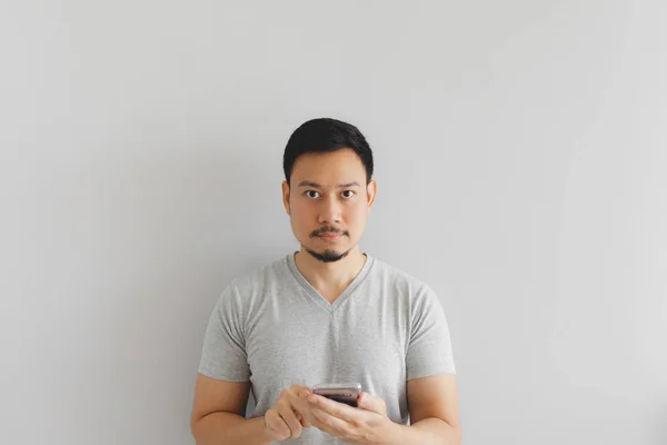 Mann im grauen T-Shirt bedient das Smartphone. — Stockfoto