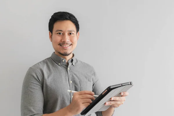 Счастливый и улыбающийся бизнесмен работает на планшете на сером фоне . — стоковое фото