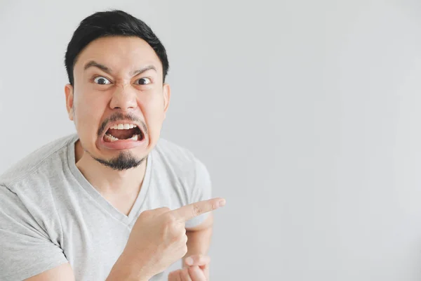 Angry face of man in grey t-shirt with hand point on empty space. — Stock Photo, Image