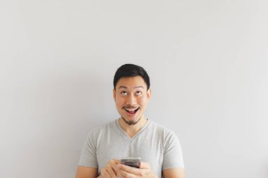 Gri tişörtlü adamın yüzü akıllı telefondan şaşırıyor..