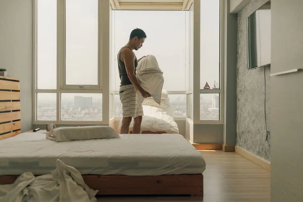 Asiático homem está limpando seu quarto com luz quente de verão . — Fotografia de Stock