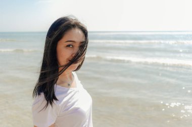 Yaz güneşli bir günde kumsalda yürüyen bir kadın..