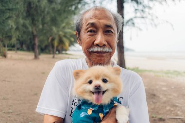 Büyükbabam elinde bir pomeranian köpeği tutuyor. Yaşlı adam en iyi arkadaş kavramı.