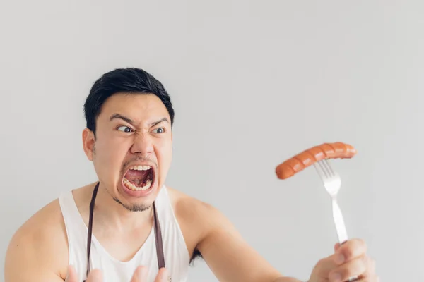 El hombre está enojado con la salchicha, ya que no es lo que esperaba para su dieta o no es delicioso . — Foto de Stock