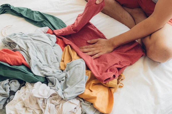 El hombre está doblando y arreglando la ropa en la cama . — Foto de Stock