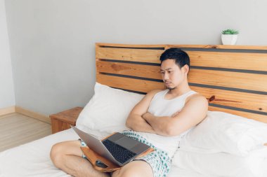 Yalnız adam onun rahat yatakta onun laptop ile çalışıyor. Freelancer iş yaşam tarzı kavramı.