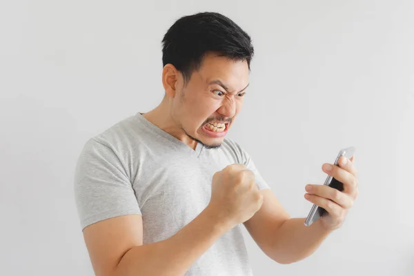 Злой мужчина в серой футболке злится на смартфон . — стоковое фото