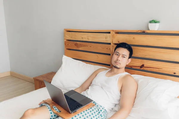 El hombre solitario está trabajando con su portátil en su acogedora cama. Concepto de freelancer estilo de vida laboral . — Foto de Stock