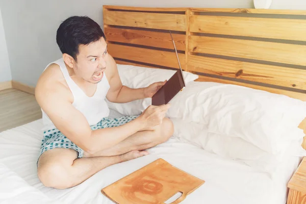 화가 남자는 자신의 침대에 자신의 노트북과 함께 일하고 있다. 프리랜서 문제 개념. — 스톡 사진