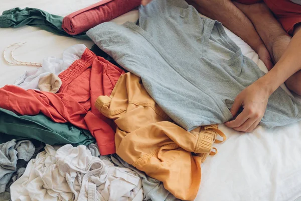 Человек складывает и расставляет одежду на кровати. . — стоковое фото