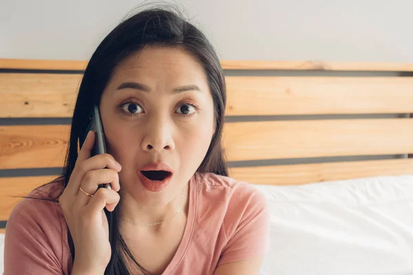 Шокированная и удивленная женщина разговаривает по телефону на своей кровати . — стоковое фото