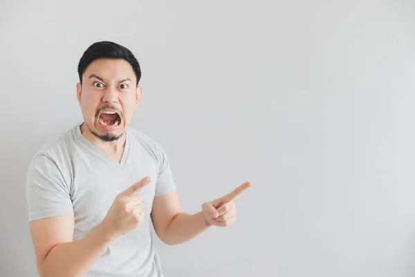 Angry face of man in grey t-shirt with hand point on empty space. — Stock Photo, Image