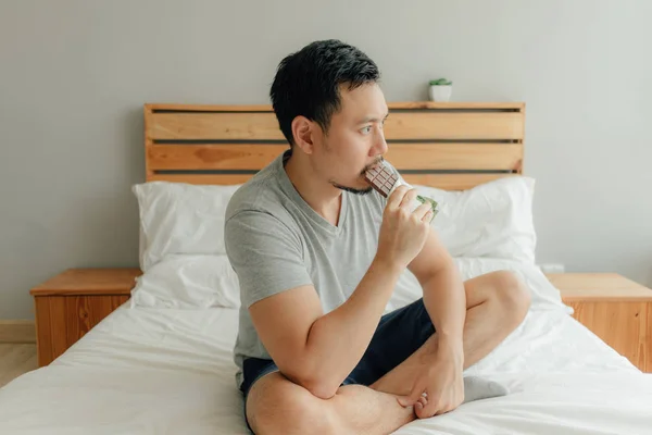 Homem está bebendo uma xícara de café na cama em seu quarto . — Fotografia de Stock
