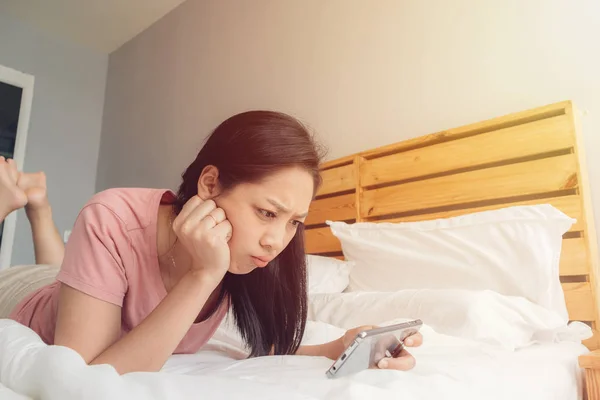 Mulher perturbada está jogando jogo móvel em sua cama . — Fotografia de Stock