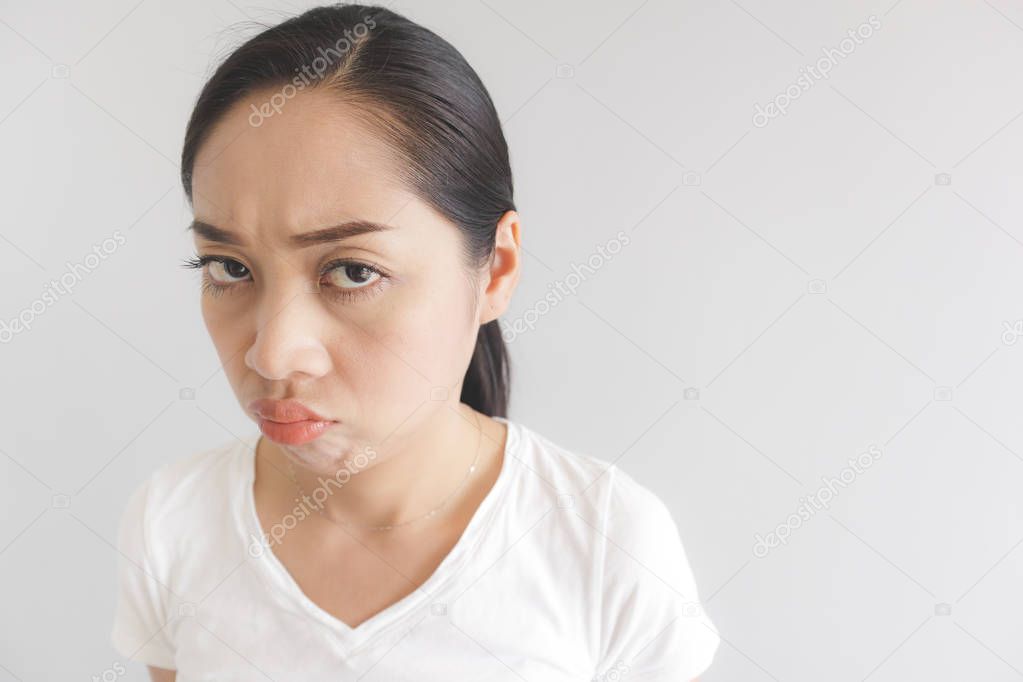 Sulk and grumpy face expression of woman in white t-shirt. Concept of offended peevish and sulky.