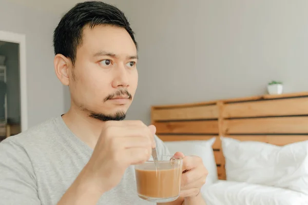 Seorang pria minum secangkir kopi di tempat tidur di kamar tidurnya . — Stok Foto