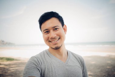 Sahildeki çam ağacının altında duran adamın yakın çekim. Açık havada rahatlatıcı konsept.