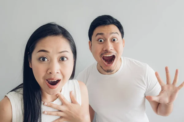 Förvånad och chockad par älskare i vit t-shirt och grå bakgrund. — Stockfoto