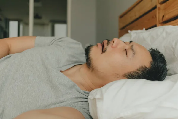 Un hombre cercano durmiendo en su cama con cara de ronquido. Concepto de ronquido . — Foto de Stock