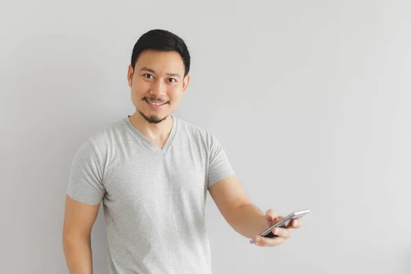 Muž v šedivém triku používá smartphone. — Stock fotografie