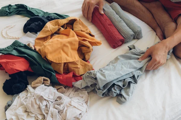 Man viker och ordnar kläderna på sängen. — Stockfoto