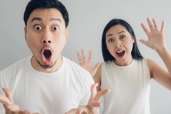 Förvånad och chockad par älskare i vit t-shirt och grå bakgrund. — Stockfoto