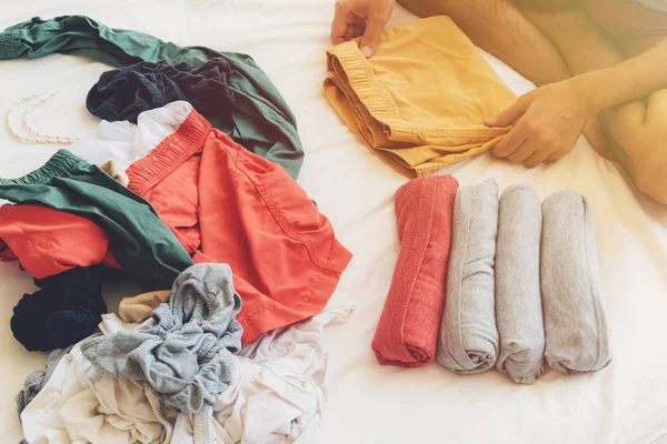 Mann faltet und arrangiert die Kleidung auf dem Bett. — Stockfoto