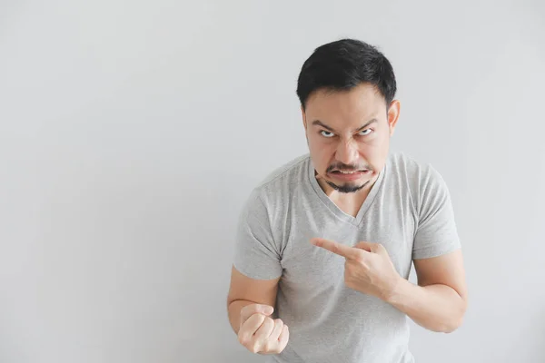 Angry face of man in grey t-shirt with hand point on empty space. — Stock Photo, Image