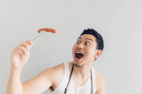 L'homme heureux mange la délicieuse saucisse préférée qu'il a cuisinée lui-même . — Photo
