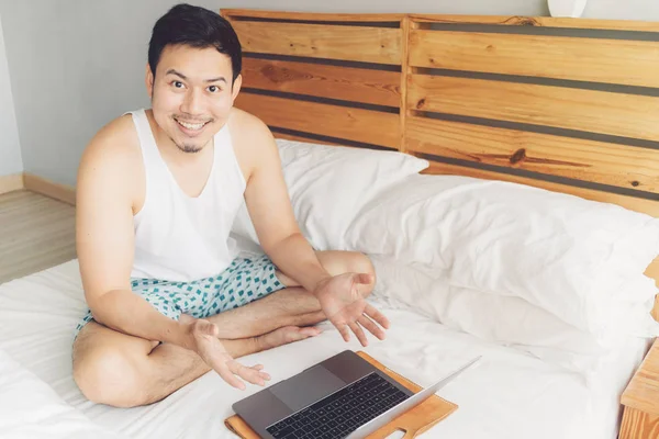 행복한 남자는 자신의 침대에 자신의 노트북으로 작업하고 있습니다. 프리랜서 성공적인 라이프 스타일의 개념. — 스톡 사진