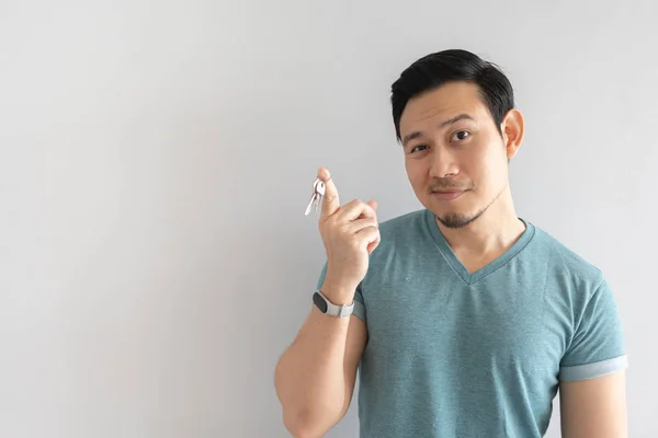 Asian man with funny face showing the key. Concept of useless key.