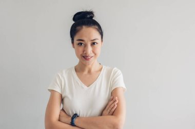 Beyaz tişörtlü ve gri arka planlı bir kadının gülen yüzü.