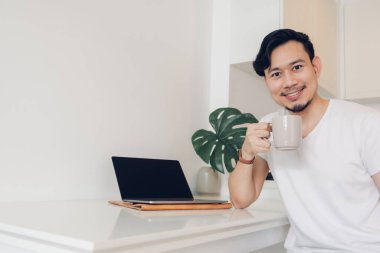 Adam dizüstü bilgisayarı üzerinde çalışıyor. Çalışma alanı beyaz ve yeşil santral..