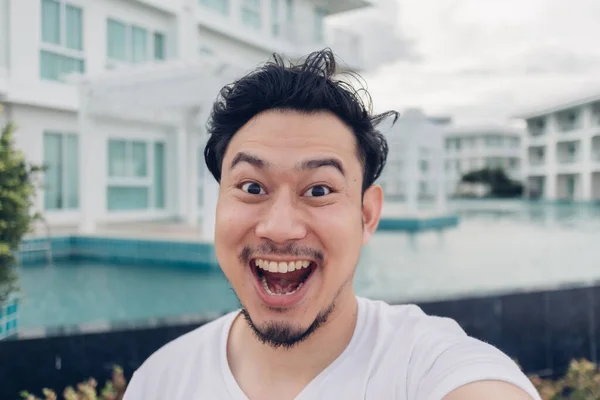 Happy face of Asian man selfie himself with luxury resort.
