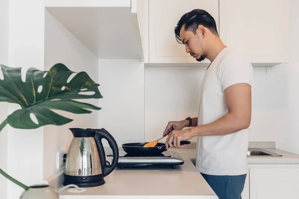 Man is cooking breakfast in the kitchen.