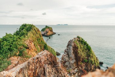 Sakin deniz ve bulutlu gökyüzü ile uçurum ve sahil.