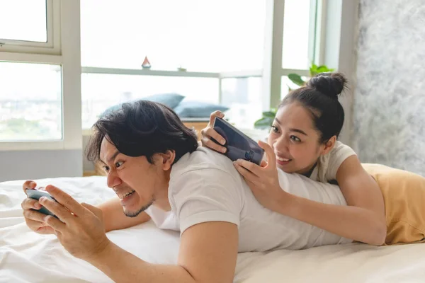 Aufgeregtes Paar spielt gemeinsam Handy in Wohnung. — Stockfoto